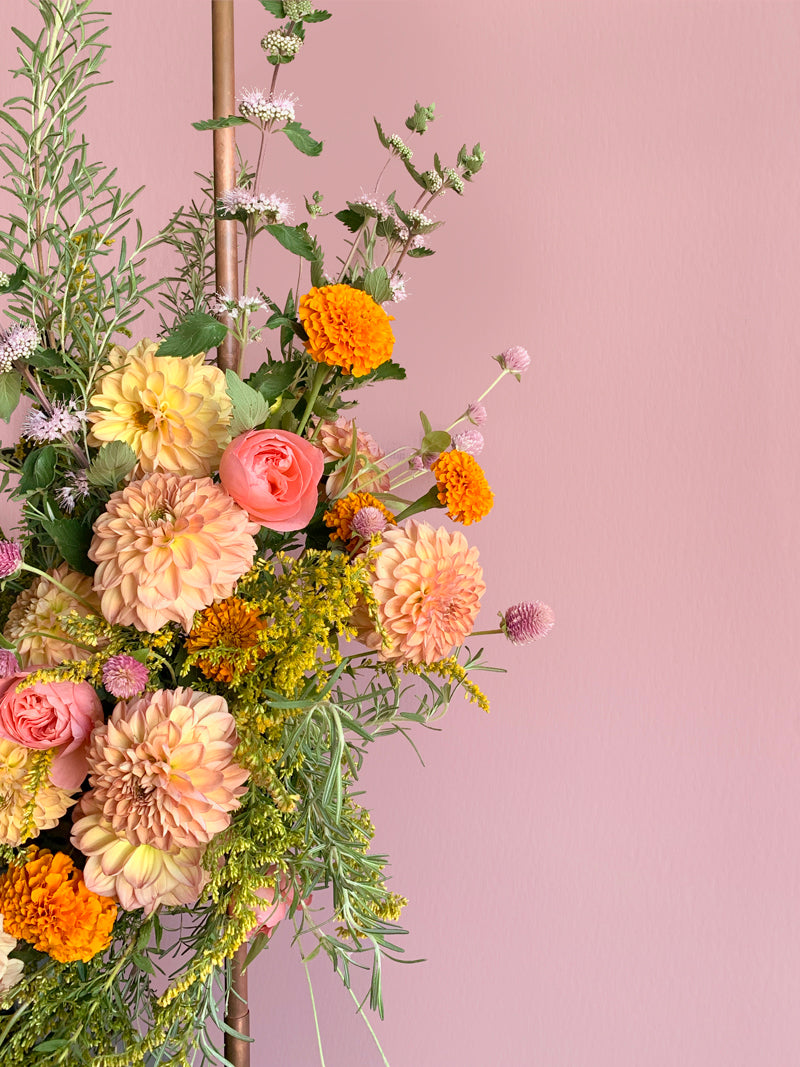 Floral arrangement with a variety of flowers on a pink background