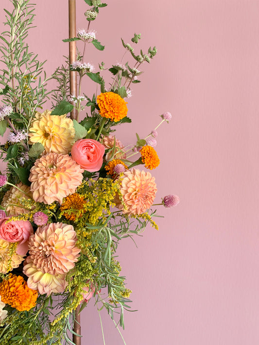 Floral arrangement with a variety of flowers on a pink background